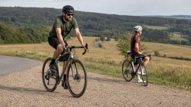 Gravel kolo se sklopenými řídítky a širokými plášti stojící na štěrkové polní cestě
