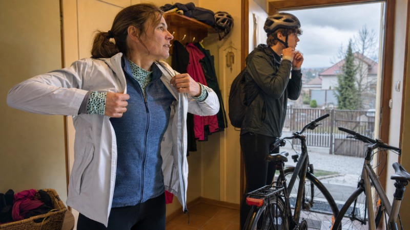 Cyklista si za jízdy svléká vrstvu oblečení, na kole má viditelné tři různé vrstvy textilu